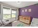 Serene Bedroom boasts a wooden crib, rocking chair, soft lighting, and purple accent wall at 389 Whispering Hills Dr, Locust, NC 28097