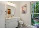 Bright powder room with a white vanity, neutral walls, and a window to a wooded yard at 5008 Saddle Horn Trl, Weddington, NC 28104