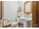 Charming powder room featuring a pedestal sink, decorative wallpaper, and hardwood flooring at 5008 Saddle Horn Trl, Weddington, NC 28104