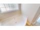 A well-lit soaking bathtub next to a window with textured glass provides privacy at 6313 Woodland Commons Dr, Charlotte, NC 28269