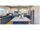 Bright eat-in kitchen with white cabinets, a stainless steel backsplash, and an island with a cooktop and pendant lighting at 6313 Woodland Commons Dr, Charlotte, NC 28269