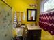 Bright yellow bathroom with a stand-up shower, a single sink vanity, and colorful decor at 6708 Nutcracker Pl, Charlotte, NC 28212