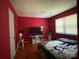 Red bedroom with hardwood floors and a TV, with a large window providing natural light at 6708 Nutcracker Pl, Charlotte, NC 28212