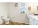 Bathroom with toilet, single vanity, window, and patterned flooring at 8330 Kneller St, Charlotte, NC 28215