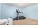 Bright bedroom featuring a treadmill, large window, and light blue walls at 8330 Kneller St, Charlotte, NC 28215