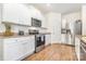 Modern kitchen boasts white cabinets, stainless steel appliances, granite countertops, and wood-look flooring at 8330 Kneller St, Charlotte, NC 28215