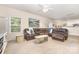 Inviting living room features a large leather sofa, neutral décor, a ceiling fan, and seamlessly connects to kitchen at 8330 Kneller St, Charlotte, NC 28215