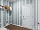 Functional laundry room with storage shelf, white door, and striped accent wall at 1056 Mapletree Ln, Indian Trail, NC 28079