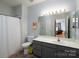 Bathroom featuring tile floors, a shower with curtain, large mirror, and grey vanity at 10614 Hill Point Ct, Charlotte, NC 28262