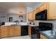 Kitchen featuring wood cabinets, marble countertops, and black appliances open to the living area at 10614 Hill Point Ct, Charlotte, NC 28262