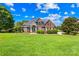 Stately two-story brick home featuring a well-manicured lawn, mature trees, and charming architectural details at 132 Broadbill Dr, Mooresville, NC 28117