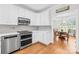 Modern kitchen showcasing stainless steel appliances, white cabinets, and hardwood floors with dining area at 132 Broadbill Dr, Mooresville, NC 28117