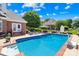 Backyard pool features a brick surround, lush landscaping, and outdoor seating area perfect for summer entertaining at 132 Broadbill Dr, Mooresville, NC 28117