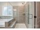 Modern bathroom with gray tiled walk-in shower, and soaking tub at 13339 Mcguffy Dr, Huntersville, NC 28078