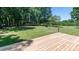 View from the wooden deck to the backyard with green grass and mature trees at 155 Mcallister Rd, Statesville, NC 28625