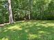 Backyard featuring a lush, green lawn shaded by mature trees, offering a serene outdoor space at 201 Barnes Ln, Stony Point, NC 28678