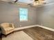 Bedroom featuring wood-look floors, gray walls, white ceiling, window, and a comfortable chair at 201 Barnes Ln, Stony Point, NC 28678