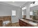 Bathroom featuring a dual sink vanity, soaking tub with tile surround, and natural lighting at 2145 Jack Wilson Rd, Shelby, NC 28150