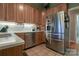 Bright kitchen with stainless steel appliances, wooden cabinetry, and a tile backsplash at 406 Spyglass Hill Pl, Salisbury, NC 28144