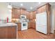 A well-lit kitchen featuring wood cabinets, white appliances, and warm wood flooring at 407 Knops Nob Rd, Mooresville, NC 28115