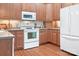 A view of a kitchen featuring wood cabinets, white appliances, and hardwood floors at 407 Knops Nob Rd, Mooresville, NC 28115