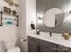 Charming powder room featuring a round mirror, patterned wallpaper, and a modern vanity with sleek fixtures at 460 E 33Rd St, Charlotte, NC 28205