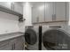 Well-organized laundry room with gray cabinets, granite countertops, and modern, front-loading washer and dryer at 460 E 33Rd St, Charlotte, NC 28205