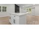 Open living area with black brick fireplace, wood floors, and white quartz kitchen island at 5534 Great Wagon Rd, Charlotte, NC 28215