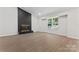 Cozy living room featuring a painted brick fireplace, large window, and wood-look flooring at 5534 Great Wagon Rd, Charlotte, NC 28215