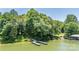 A beautiful view of a wooden dock extending into the serene lake, surrounded by lush green trees and foliage at 584 Williamson Rd, Mooresville, NC 28117