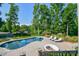 Backyard view of the in-ground swimming pool with surrounding patio, lounge chairs and mature landscaping at 711 Yadkin St, Albemarle, NC 28001
