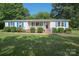 Inviting single-story home with a well-manicured lawn, blue shutters, and a cozy front porch at 7645 Robinson Church Rd, Harrisburg, NC 28075