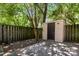 Fenced backyard with mature trees and storage shed offering extra space for lawn and garden equipment at 8266 Knights Bridge Rd, Charlotte, NC 28210