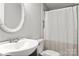 Bright bathroom with an oval mirror, single sink vanity, and a shower with a white curtain at 8266 Knights Bridge Rd, Charlotte, NC 28210