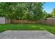 A level backyard featuring green grass, wooden fence and trees at 8325 Burgundy Ridge Dr, Harrisburg, NC 28075