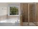 Bathroom showcasing a tub, tiled shower, and window with natural light at 8325 Burgundy Ridge Dr, Harrisburg, NC 28075