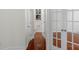 Hallway view featuring wood flooring, white trim, and doors to a bathroom and office at 8325 Burgundy Ridge Dr, Harrisburg, NC 28075