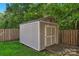 A wooden shed with double doors, a wooden ramp, and a neutral color scheme nestled in a grassy backyard at 8325 Burgundy Ridge Dr, Harrisburg, NC 28075