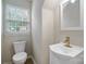 Cozy half-bath with white vanity, gold fixtures, and a window providing natural light at 8343 Highlander Ct, Charlotte, NC 28269