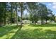 The back of the home features mature trees, a spacious yard, and fencing at 8529 Indian Summer Trl, Harrisburg, NC 28075