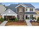 Stylish two-story home featuring brick and gray siding with a well-maintained lawn, and rocking chairs on the front porch at 1045 Waxhaw Crossing Dr, Waxhaw, NC 28173