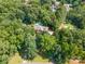 Aerial view of a brick home on a large wooded lot with a pool and long drive at 1134 Willow Oaks Trl, Matthews, NC 28104