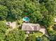 Aerial view of a brick home on a large wooded lot with a pool and long drive at 1134 Willow Oaks Trl, Matthews, NC 28104