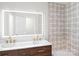 Modern bathroom with dual sinks, wood vanity, and decorative tile accent wall in the shower at 1134 Willow Oaks Trl, Matthews, NC 28104