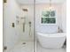 Luxurious bathroom featuring a glass shower, soaking tub, and elegant lighting at 1134 Willow Oaks Trl, Matthews, NC 28104