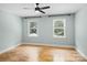 Light-filled bedroom features two windows, light blue walls, a ceiling fan, and hardwood floors at 1134 Willow Oaks Trl, Matthews, NC 28104