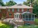 A traditional two-story brick home with a deck and screened porch in a wooded lot at 1134 Willow Oaks Trl, Matthews, NC 28104