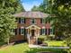 Charming brick home with a manicured lawn, lush trees, and classic architectural details at 1134 Willow Oaks Trl, Matthews, NC 28104