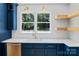 Bright kitchen with stainless appliances, white countertops, wooden floating shelves, and blue cabinets at 1134 Willow Oaks Trl, Matthews, NC 28104