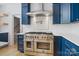 This kitchen features stainless appliances, an oversized range, custom backsplash, and blue cabinets at 1134 Willow Oaks Trl, Matthews, NC 28104